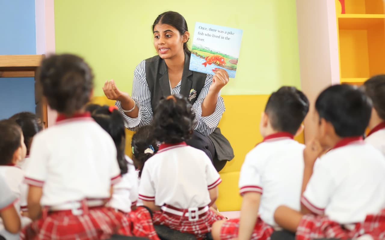 A teacher reading a book aloud while teaching young children in a classroom.