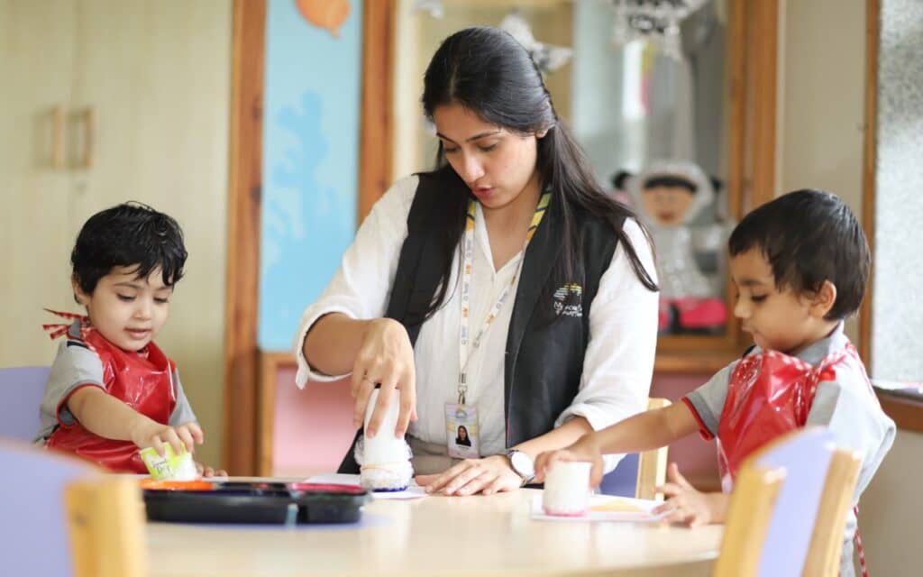 A teacher engaging young children in a fun learning activity using play crafts in a classroom.